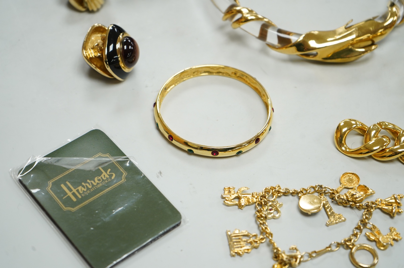 A small group of assorted costume jewellery including a 925 and paste set brooch and pair of ear clips and a gilt metal charm bracelet.